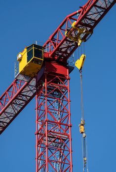 Close-up of a red tower crane operating under a clear blue sky, ideal for construction themes.