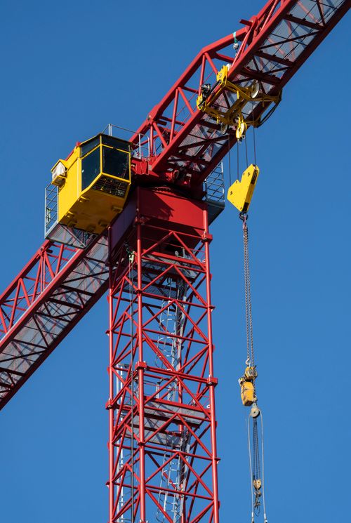 Free Close-up of a red tower crane operating under a clear blue sky, ideal for construction themes. Stock Photo