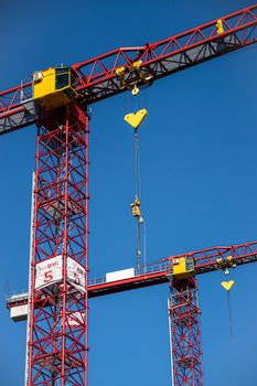 Red and yellow tower cranes against a blue sky, capturing modern construction machinery.
