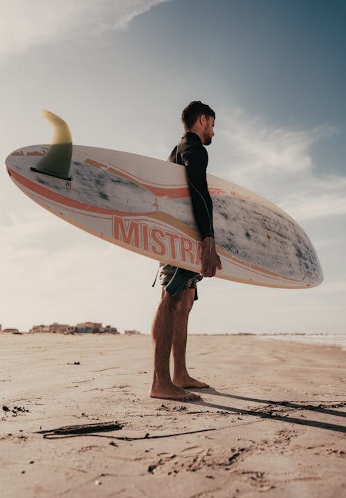 Man Standing on a Beach with a Surfboard