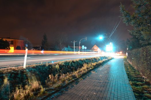 Illuminated urban street scene with light streaks and motion blur at night, capturing dynamic city life.