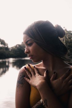 Side view portrait of a thoughtful woman near a tranquil lake surrounded by nature.