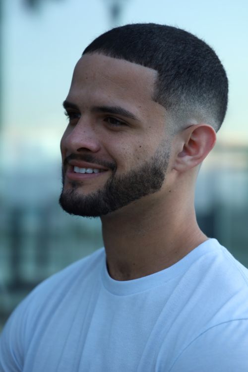 Free A smiling young man in a white shirt captured in a close-up portrait outdoors. Stock Photo