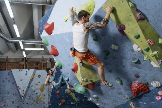 Two adults engaged in indoor rock climbing on a colorful wall, showcasing athleticism and focus.