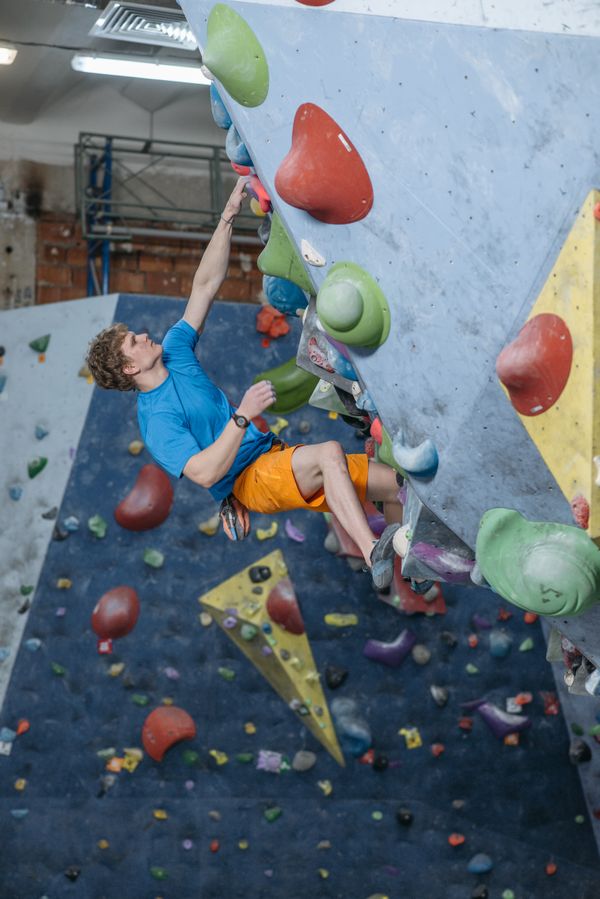 Persona practicando búlder en una pared de escalada