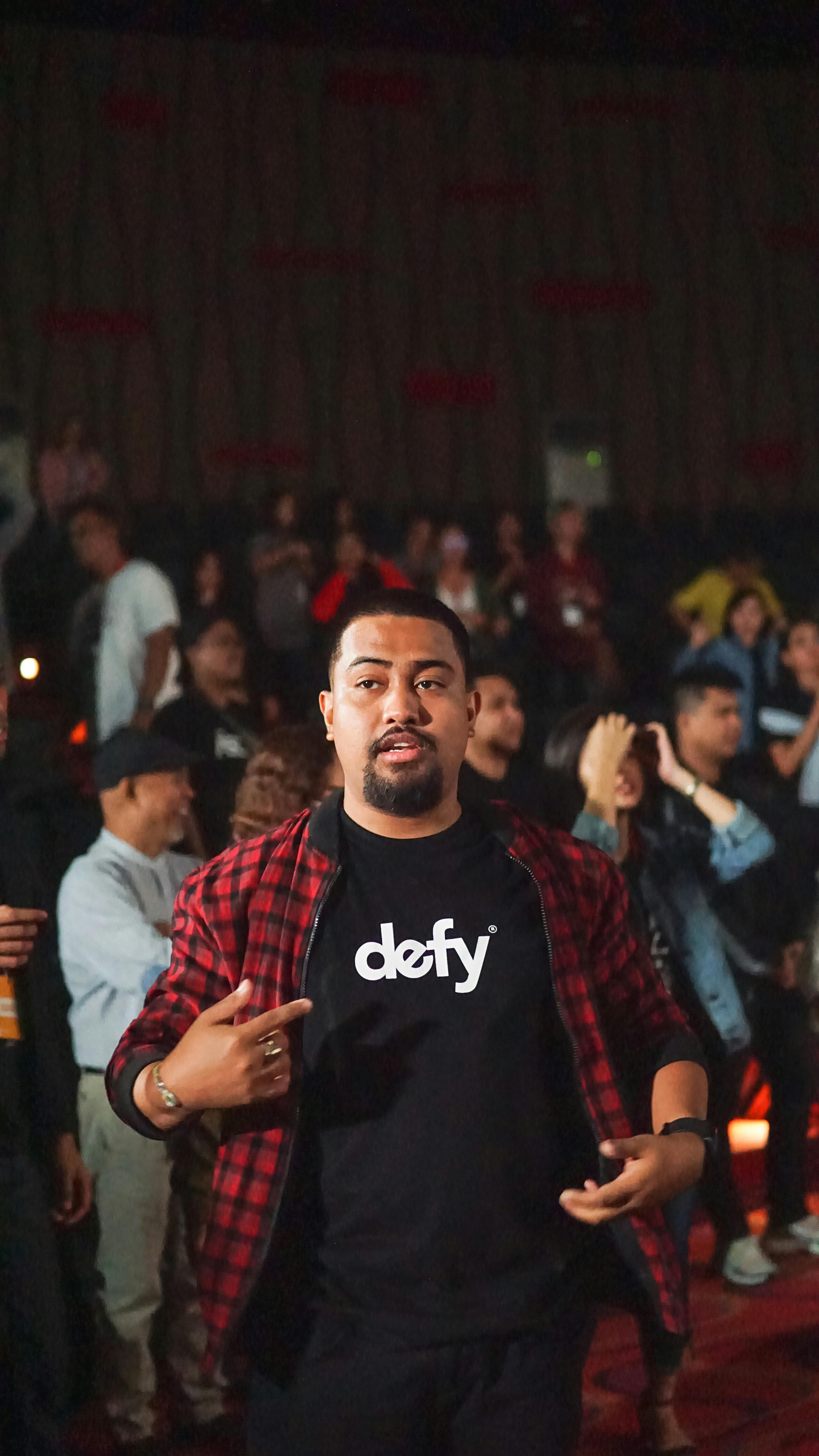 A dynamic man captivates a diverse audience during an indoor event, radiating energy and engagement.