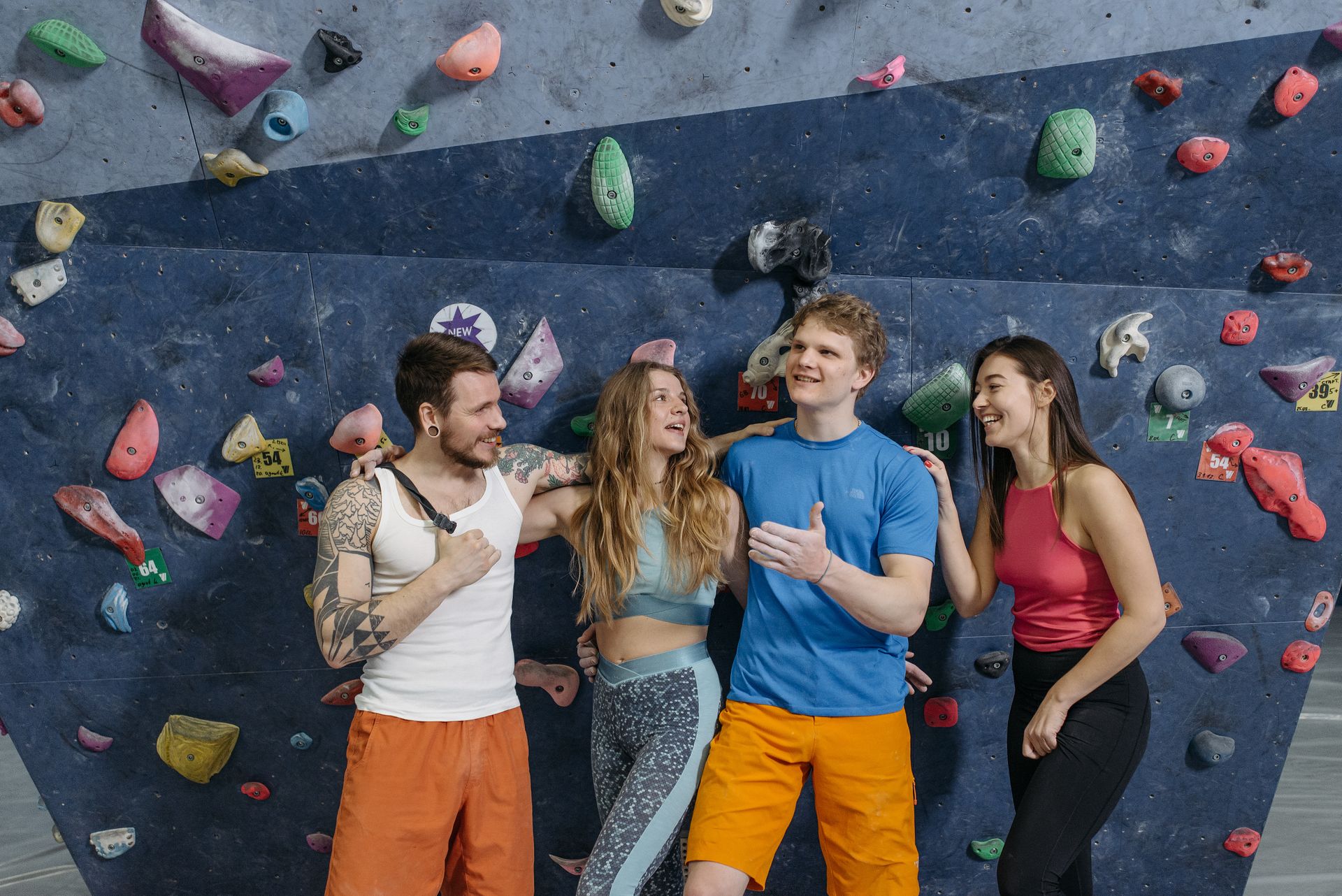 A group of friends laughing and bonding while posing at an indoor climbing wall.