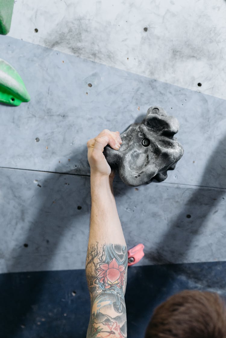 A Person Gripping On A Black Climbing Hold