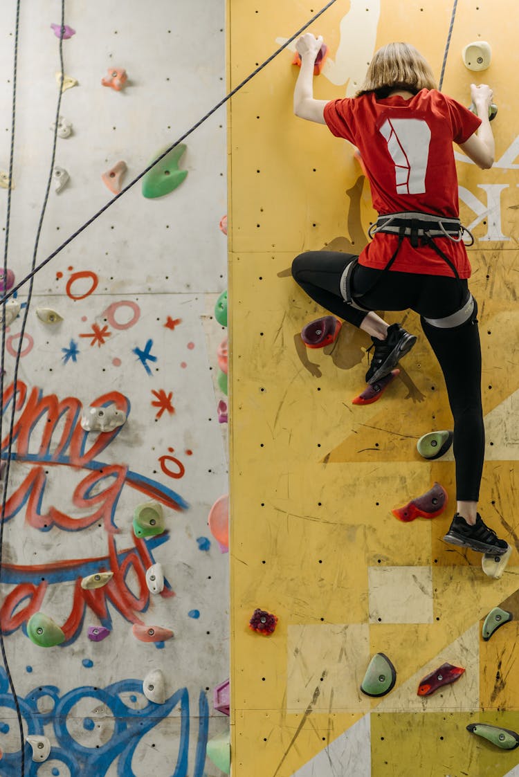 Person Holding On The Grips Climbing Down A Wall