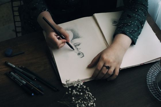 Artist sketching on a pad with pencils — photo by Merve on Pexels