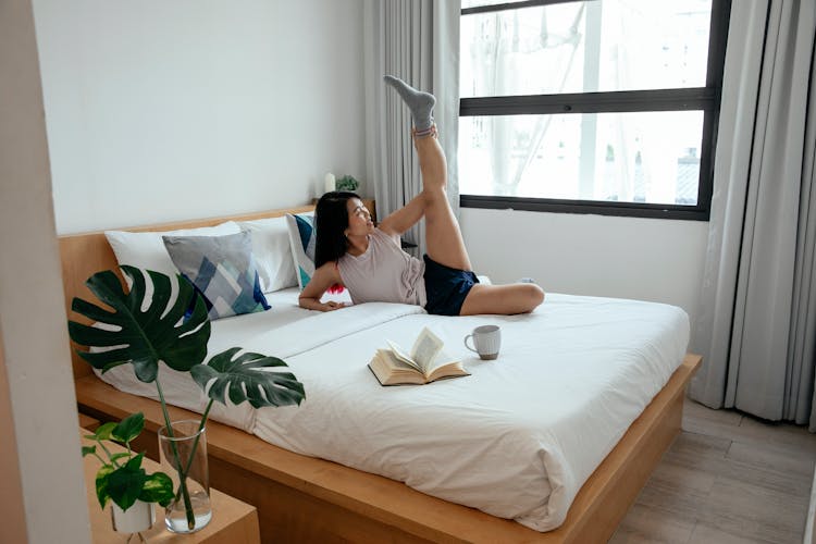 Woman In Tank Top Laying On Bed Stretching Her Leg