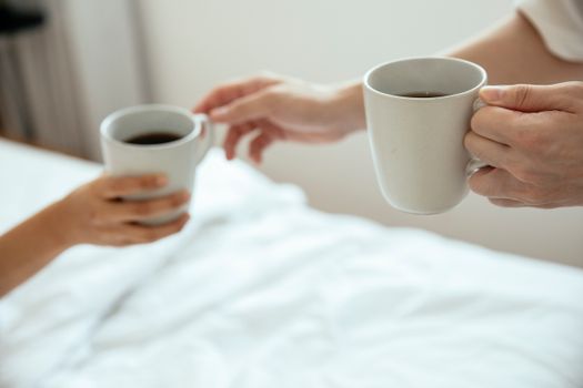 Two people enjoying morning coffee in bed, sharing warmth and comfort.