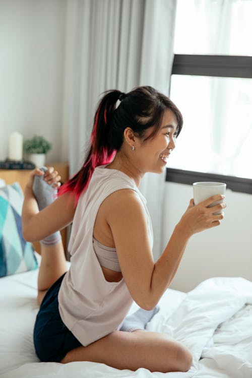 Woman Holding Cup While Stretching Herb Leg