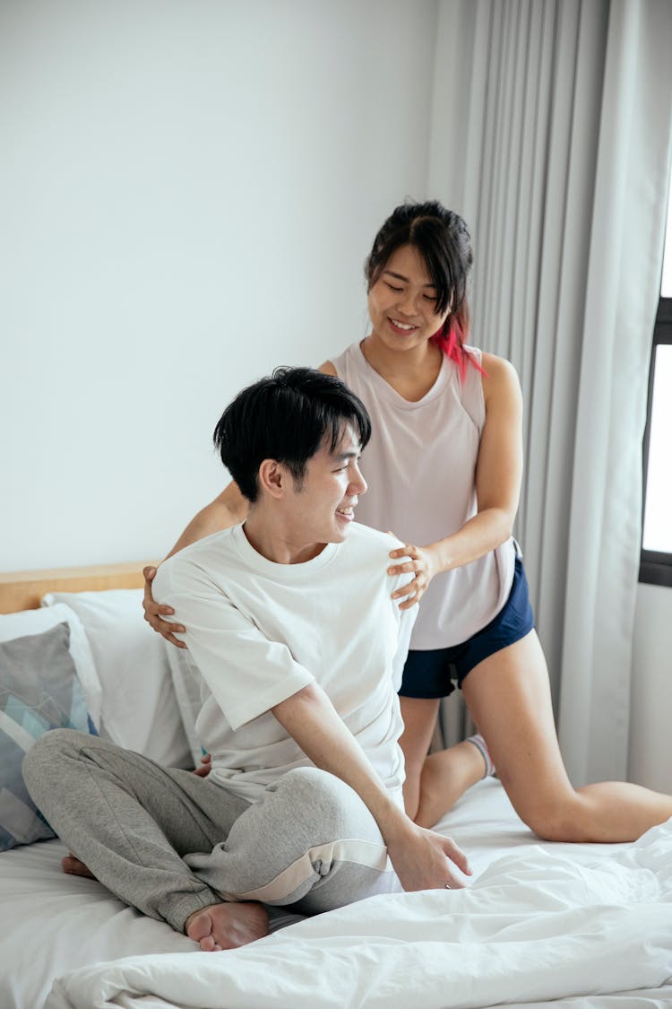 Happy Asian Couple Embracing On Bed