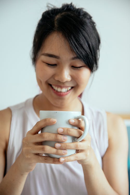 Free Smiling ethnic woman drinking coffee from cup in house Stock Photo