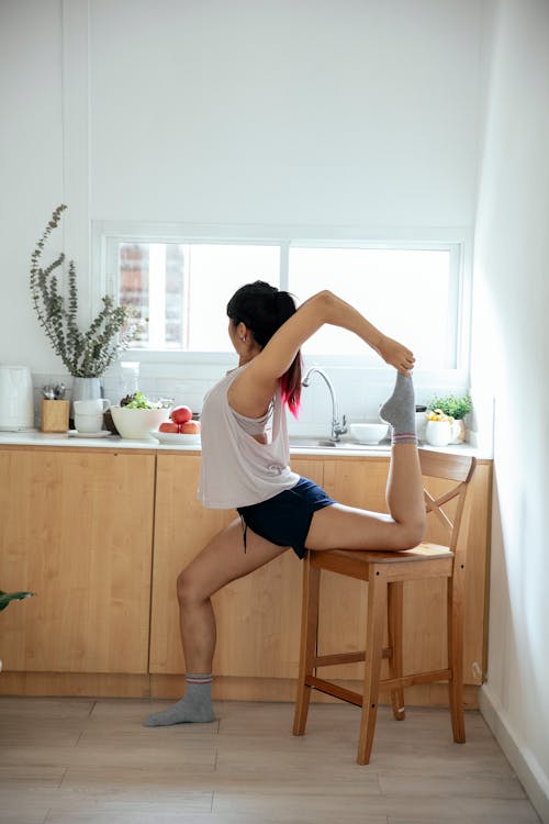 Woman stretching leg in kitchen at sunlight
