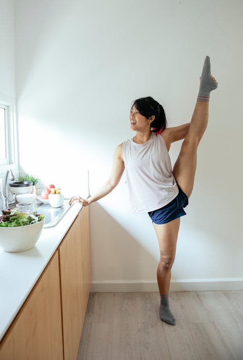 Free Ethnic lady doing splits near counter in kitchen Stock Photo