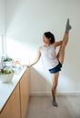 Ethnic lady doing splits near counter in kitchen