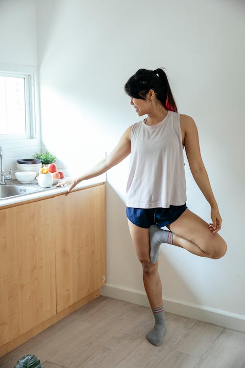 Ethnic lady doing exercise near counter in kitchen