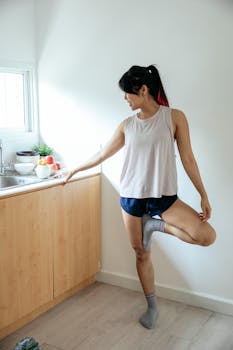 A young woman practicing yoga in a modern kitchen, embracing a healthy lifestyle.