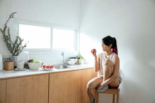 Ethnic woman eating apple in kitchen