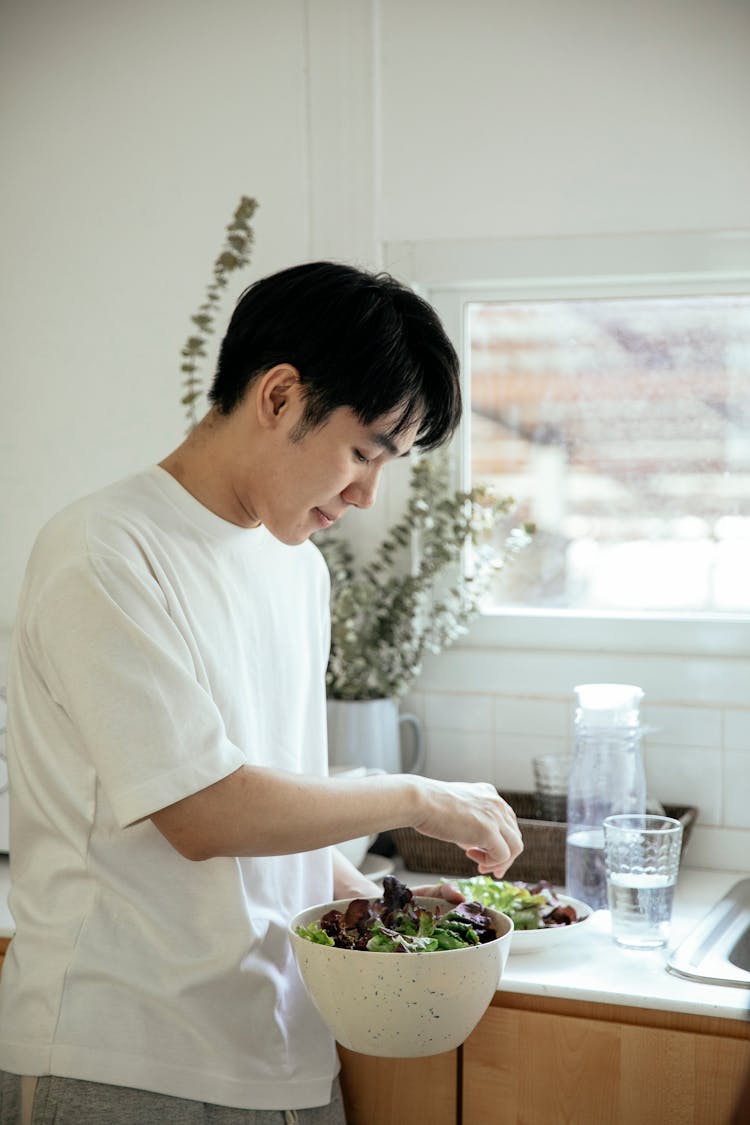 Asian Man Serving Salad Into Plate