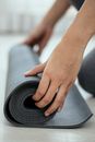 Crop female holding rolled mat on floor