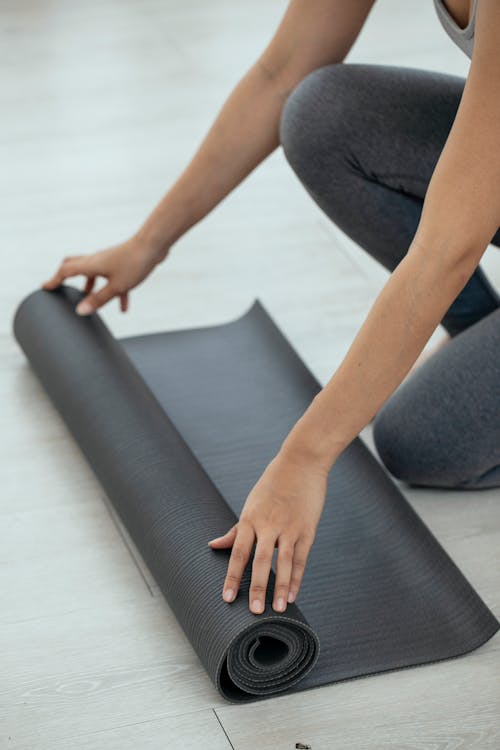 Free Crop woman unrolling mat in gym Stock Photo