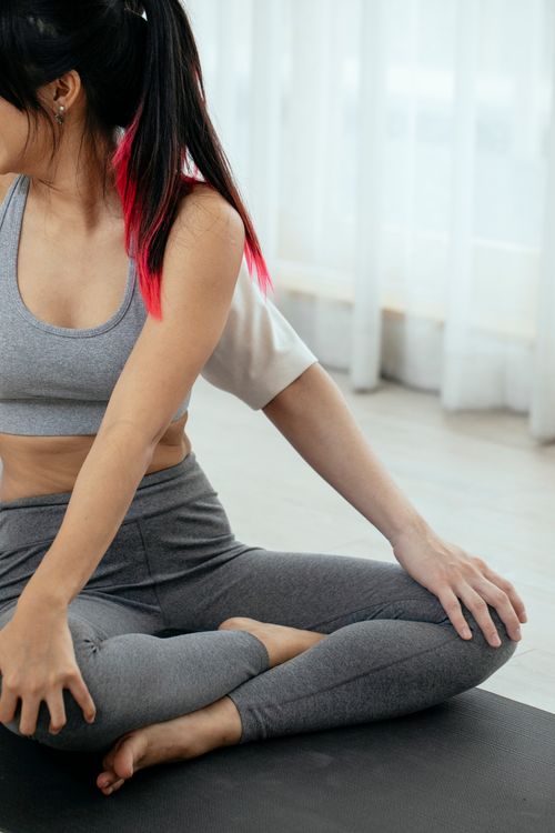 Free Crop anonymous barefoot female in activewear sitting in Padmasana pose while doing yoga with help of instructor Stock Photo
