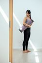 Woman with yoga mat in light room