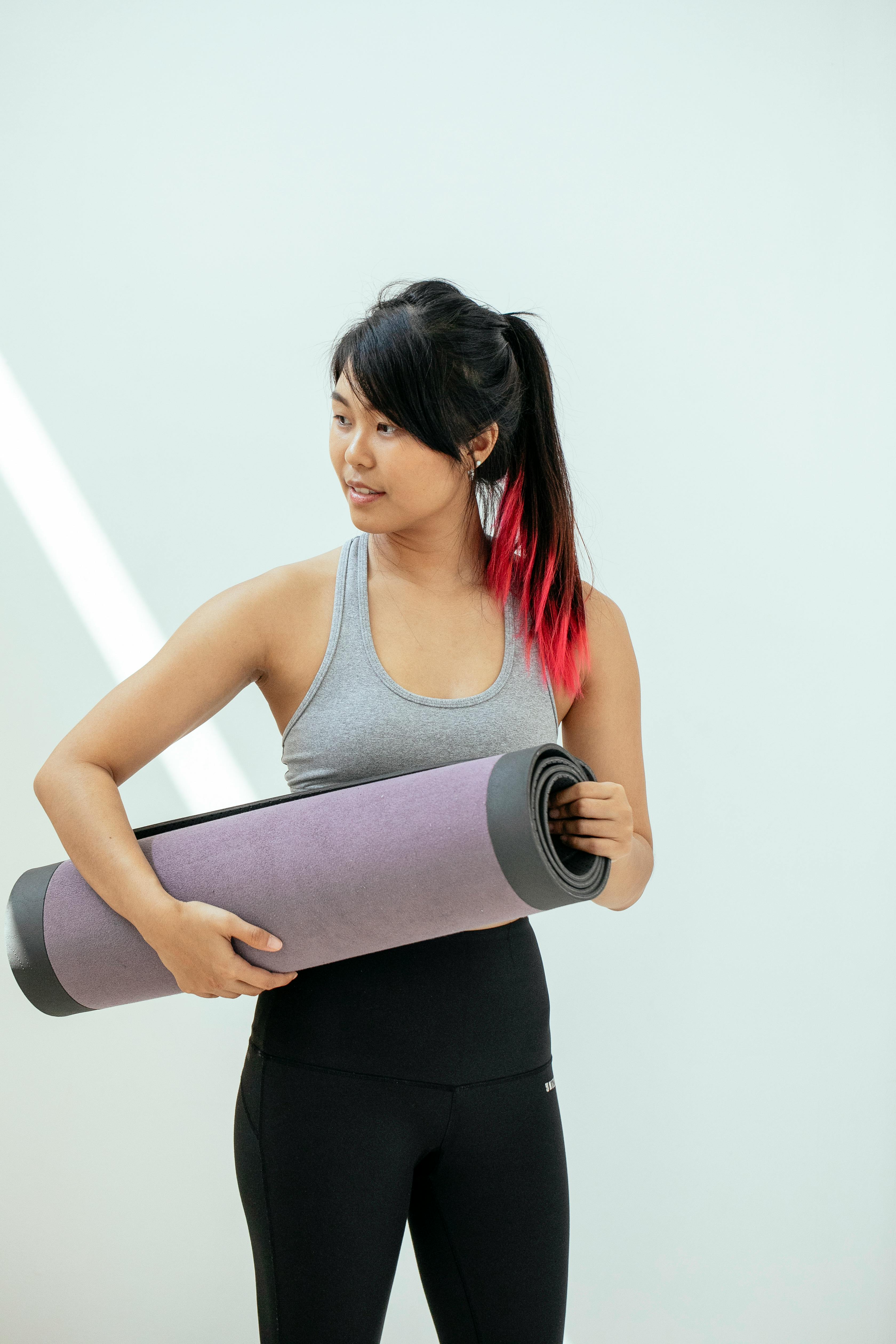 fit asian woman with rolled yoga mat