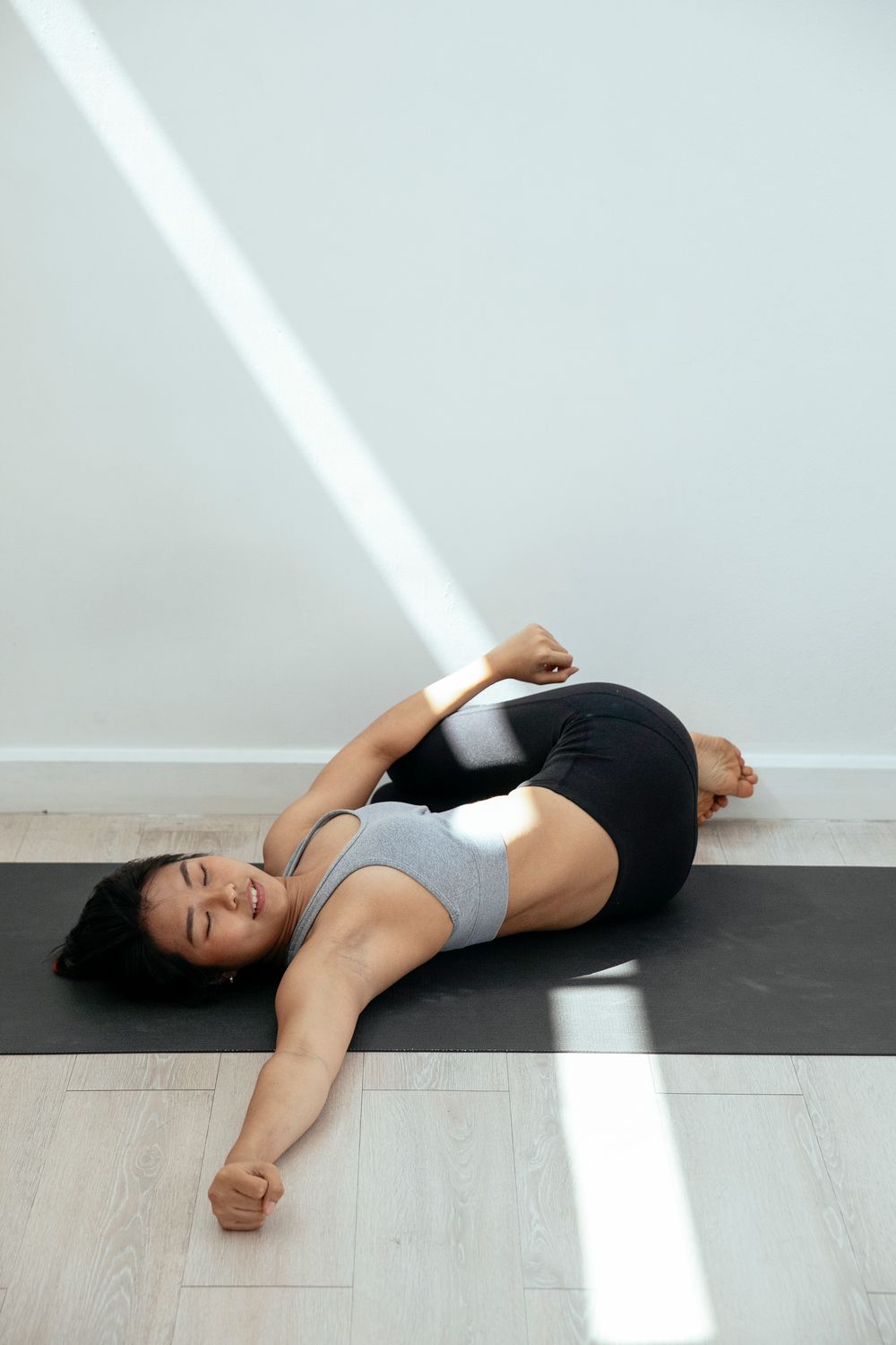Mulher fazendo rotação de quadril deitada em tapete de yoga