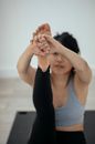Focused flexible ethnic female stretching legs and practicing yoga in Navasana on mat at home