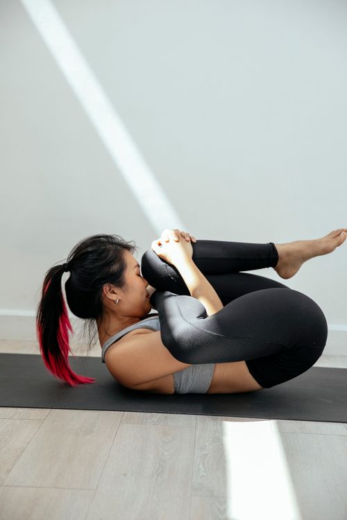 Ethnic woman doing yoga in Wind Removing pose