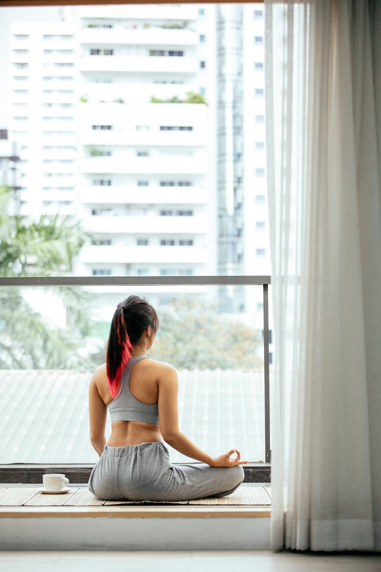 Woman Meditating In Lotus Pose On Terrace