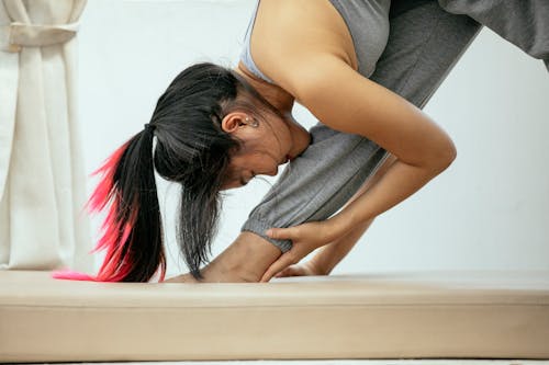 Calm ethnic woman doing yoga in Pyramid pose