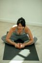 Flexible young ethnic woman performing Bound Angle asana during yoga practice