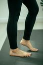 Crop anonymous barefoot female warming up toes of foot while practicing yoga on mat in room