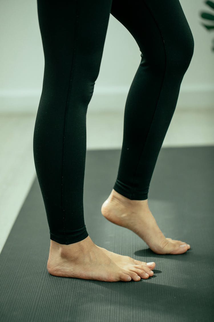 Crop Unrecognizable Woman Warming Up Foot On Yoga Mat