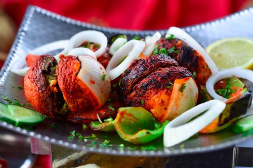Free Savor the vibrant flavors of grilled vegetables featuring onions, green peppers, and tomatoes garnished with fresh herbs. Stock Photo
