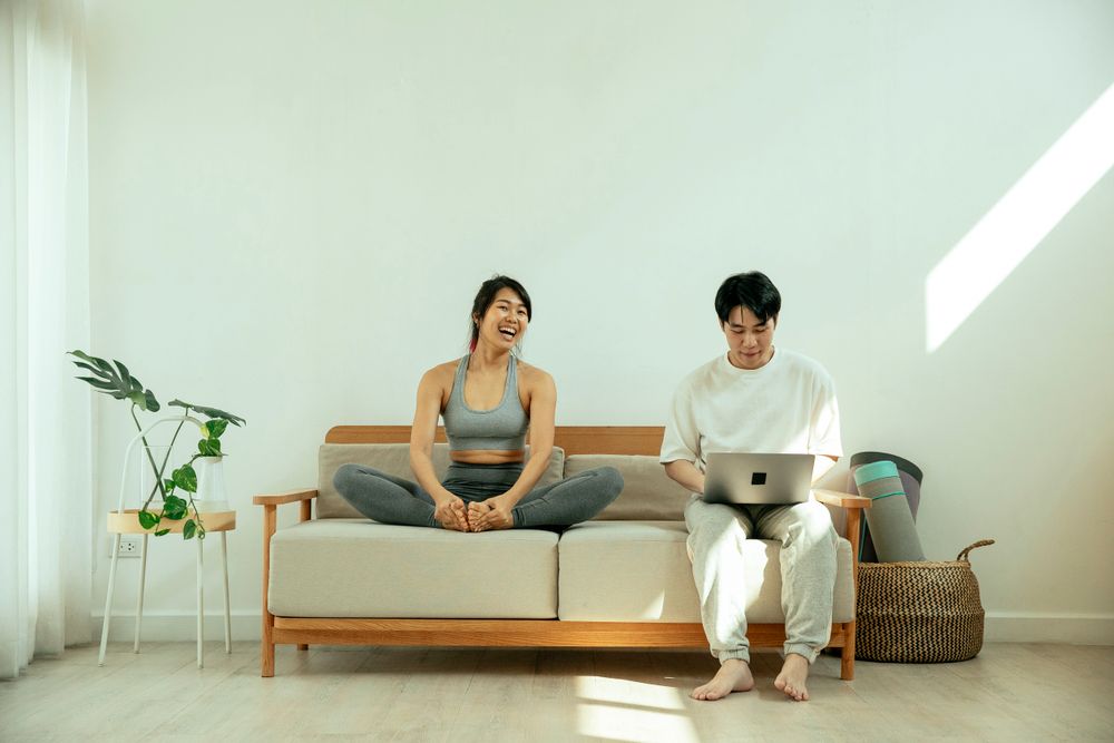 Cặp đôi ngồi cạnh nhau trên sofa cùng đọc trên laptop
