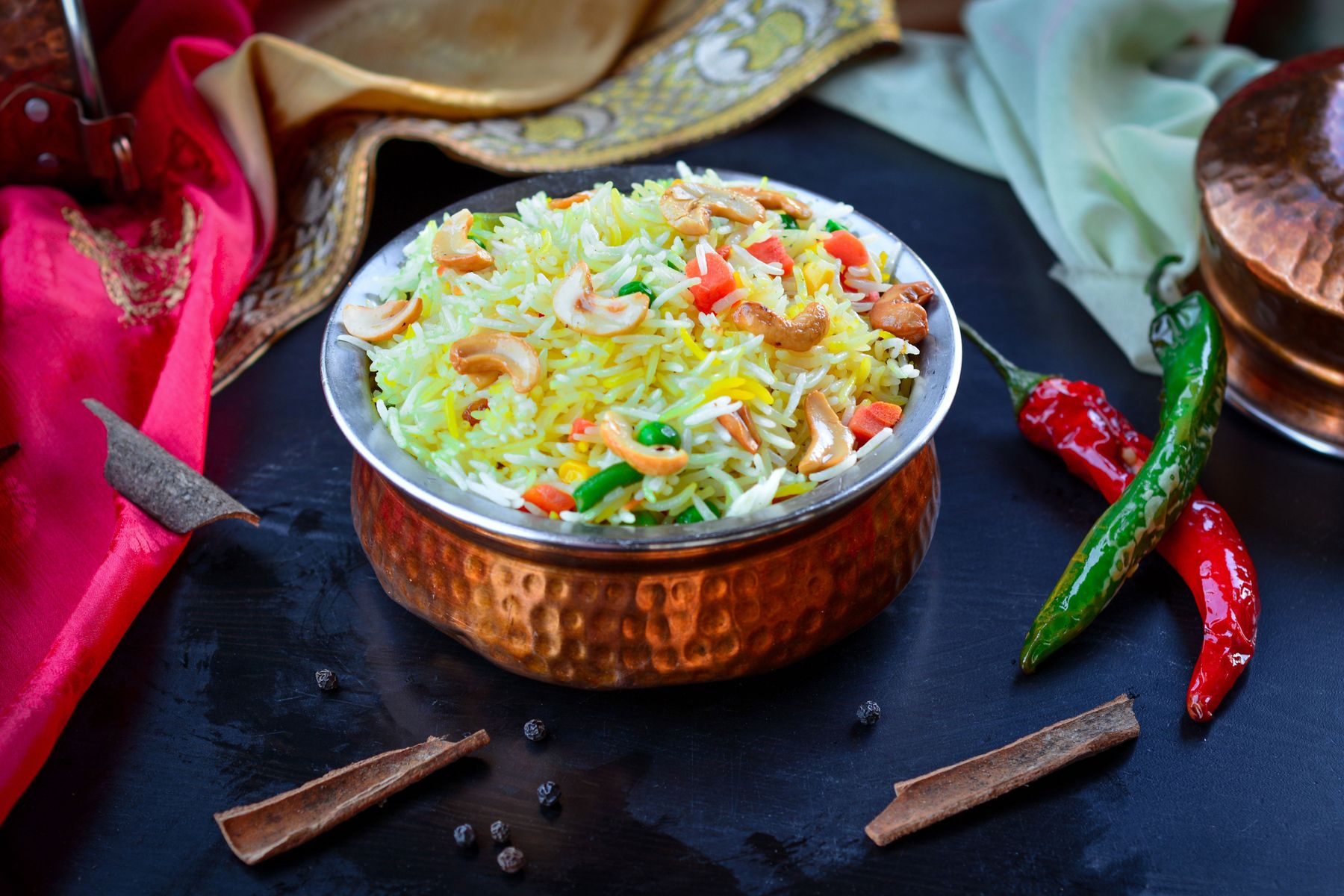 Indian biryani in a copper bowl with herbs and spices