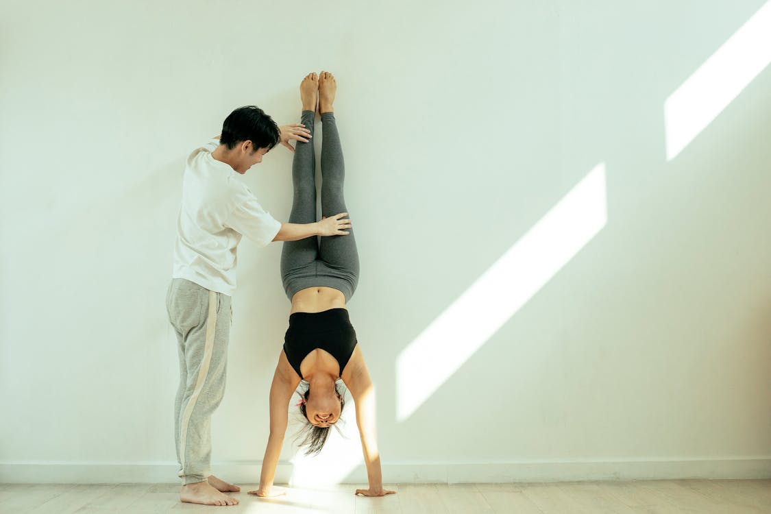 Person helping another person doing handstand at a wall