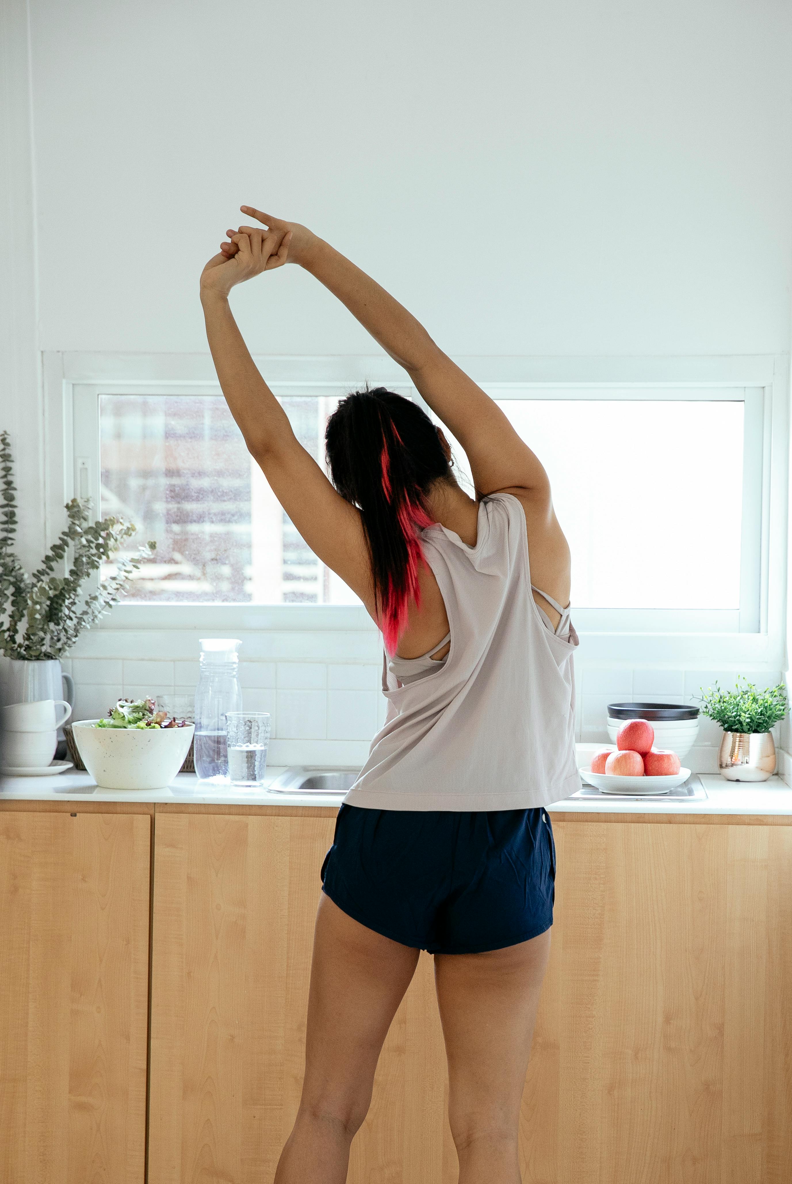 anonymous woman stretching in kitchen