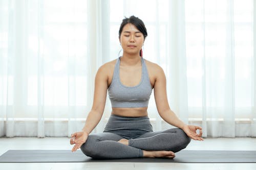 Free A Woman Meditating While Sitting on a Yoga Mat Stock Photo