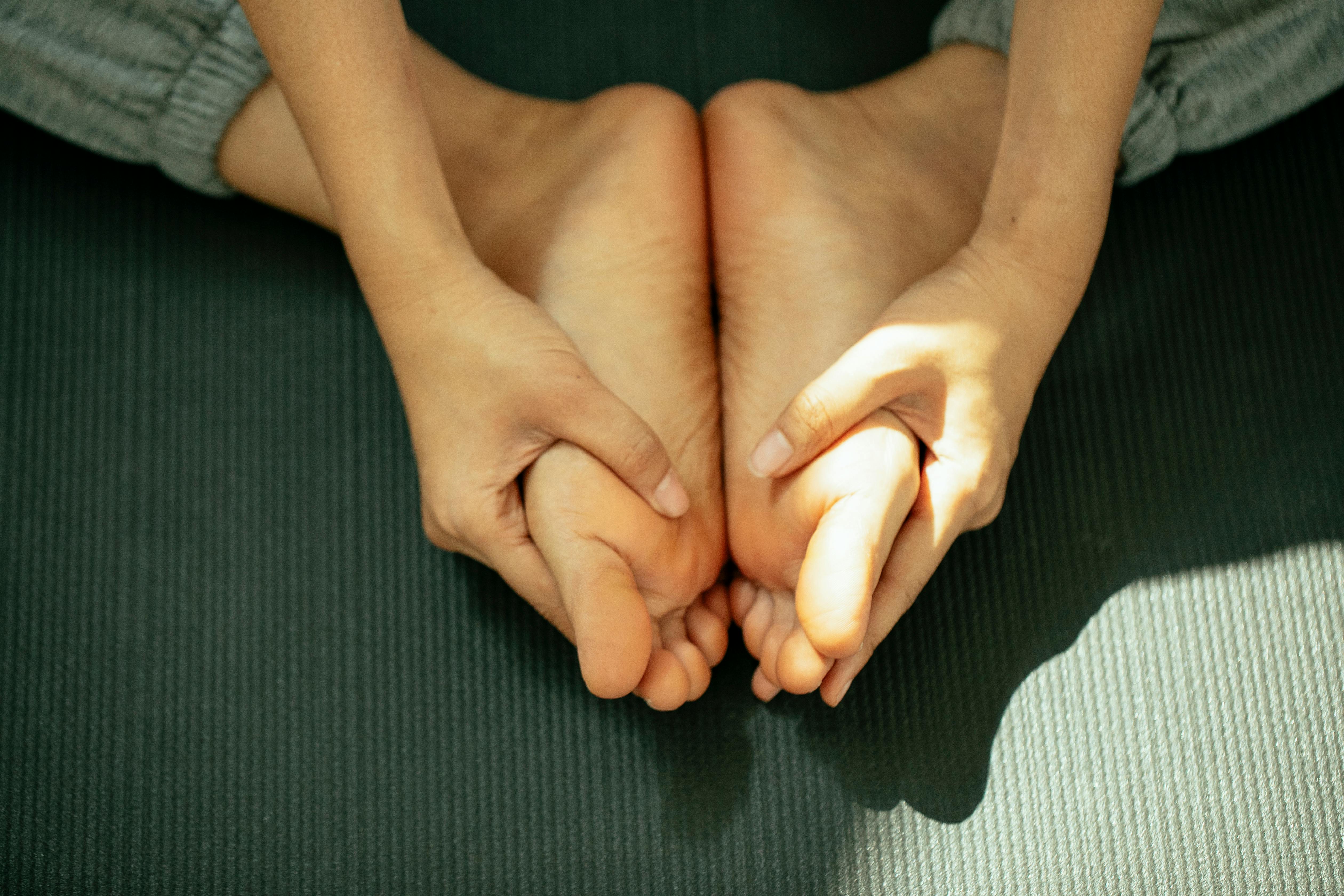 crop unrecognizable woman touching feet while practicing bound angle yoga pose