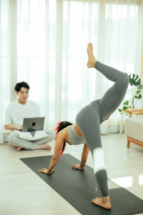 Unrecognizable fit woman practicing yoga near ethnic boyfriend browsing netbook