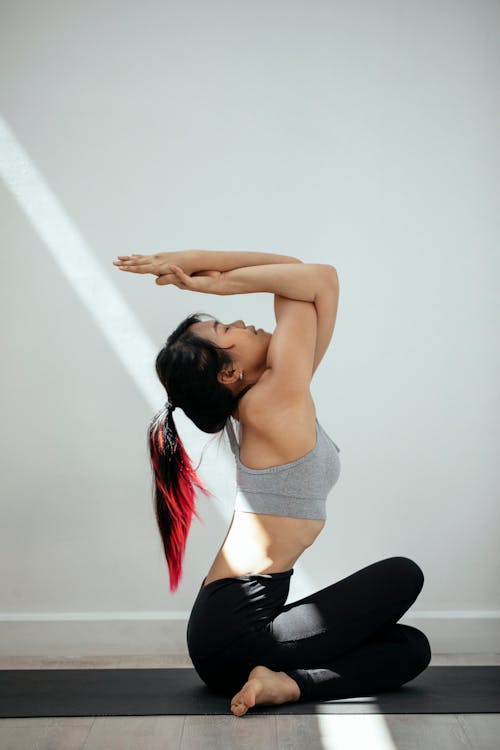 Flexible Asian woman practicing yoga on floor · Free Stock Photo