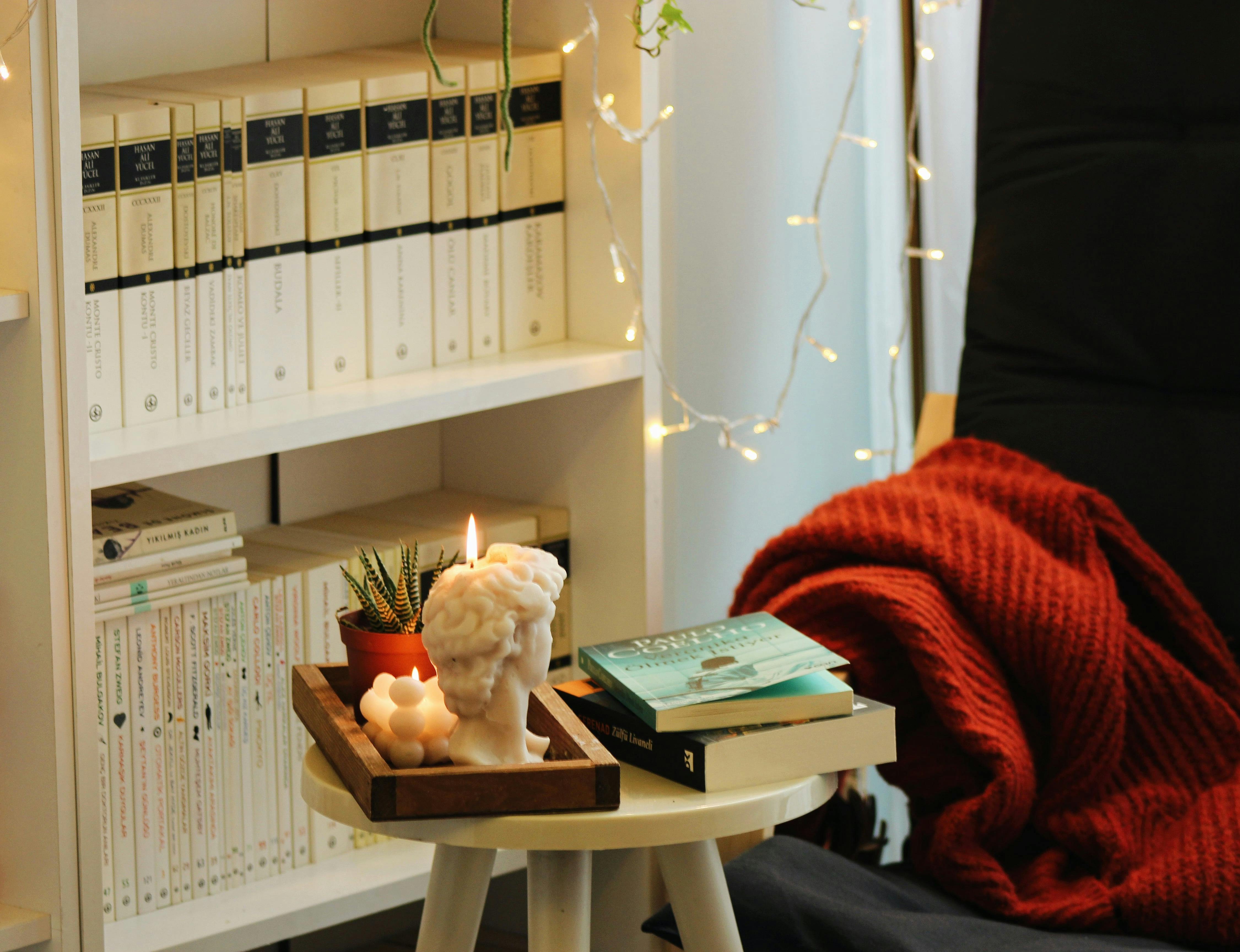 A warm and inviting living room featuring books, a candle, and cozy lighting.