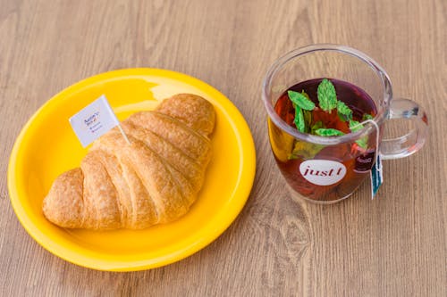 Free Croissant Bread on Yellow Plate Beside a Cup of Tea  Stock Photo